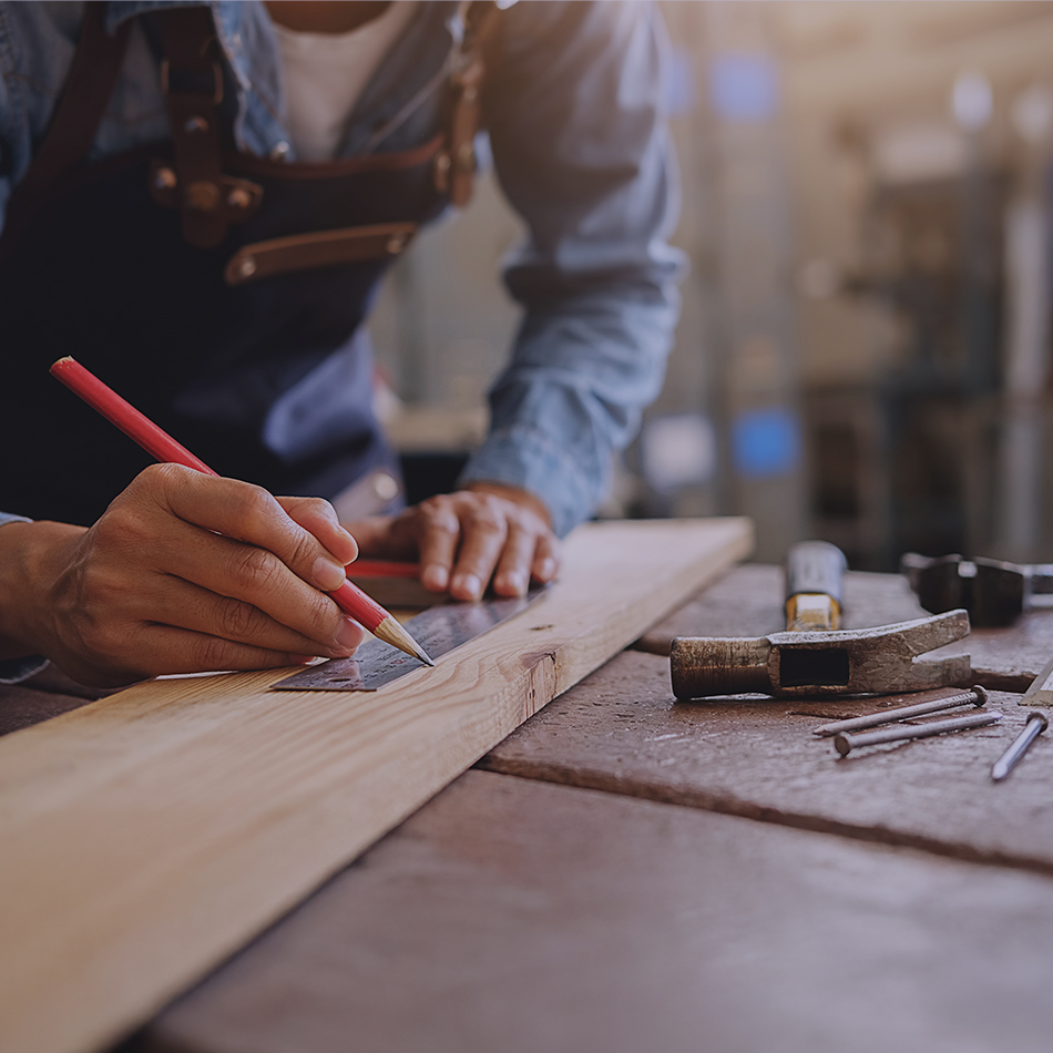 man measuring a piece of wood in a workshop