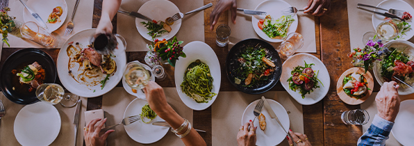 top down shot of a table full of plates of food that people are eating off