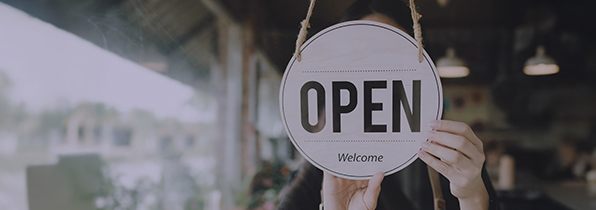 someone turning an 'open' sign round in a shop door