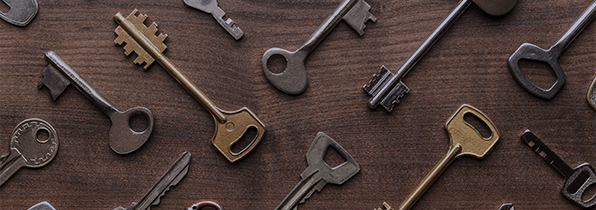 lots of different shaped and sized house keys on a wooden surface