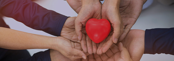 people holding their hands out collectively in a circle holding a heart shape